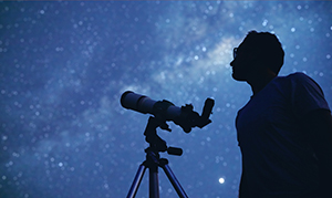man with telescope looking at up the sky at night 
