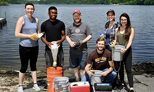 group of students outside a pond with buckets