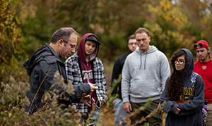 students with faculty outside studying plant life