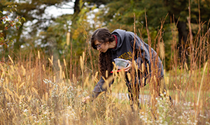 student outside in grassy wooded area