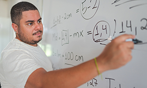 man writing math formulas on whiteboard