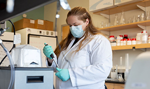 student with mask working on experiment in lab