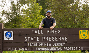 student standing behind tall pines state reserve sign