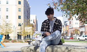 student outside writing in notebook
