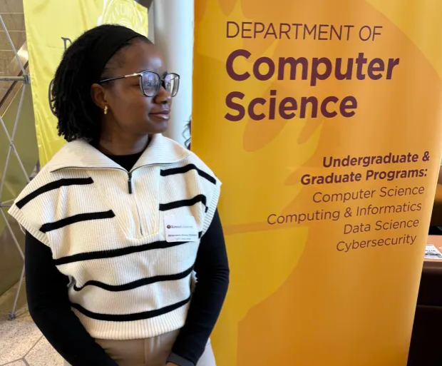 A picture of a woman standing next to a Department of Computer Science Banner.