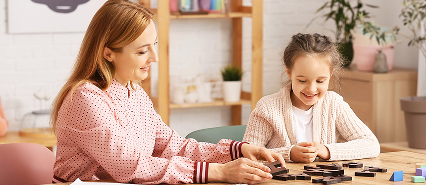 teacher working on puzzle with student at desk