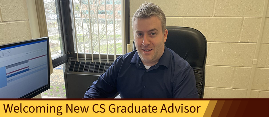 An image of new graduate advisor Michael Schillo smiling while working in his office. 