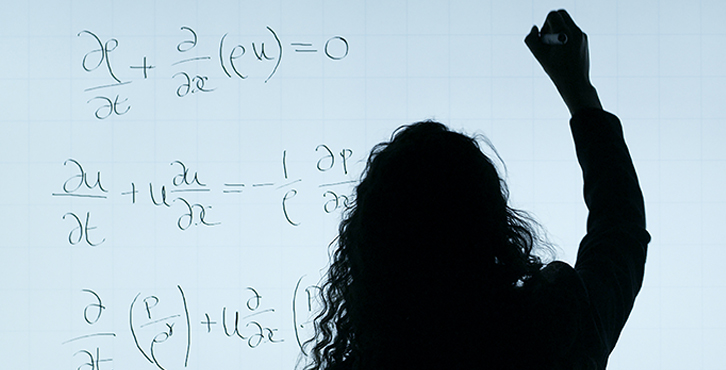 woman writing math equations on white board