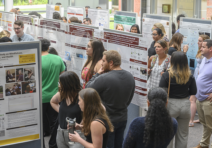 students at research conference looking at posters that present research findings