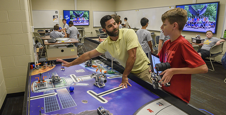 boy working with professor on lego project on large table