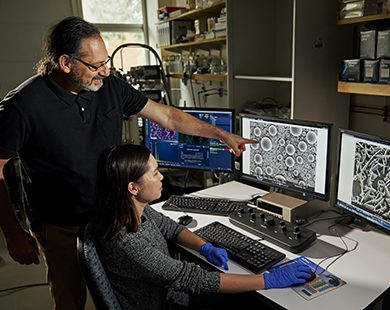 man and woman pointing at research images on computer