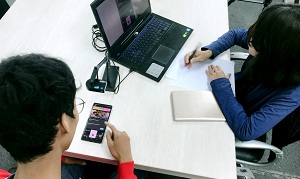 Students working on laptop and smart phone