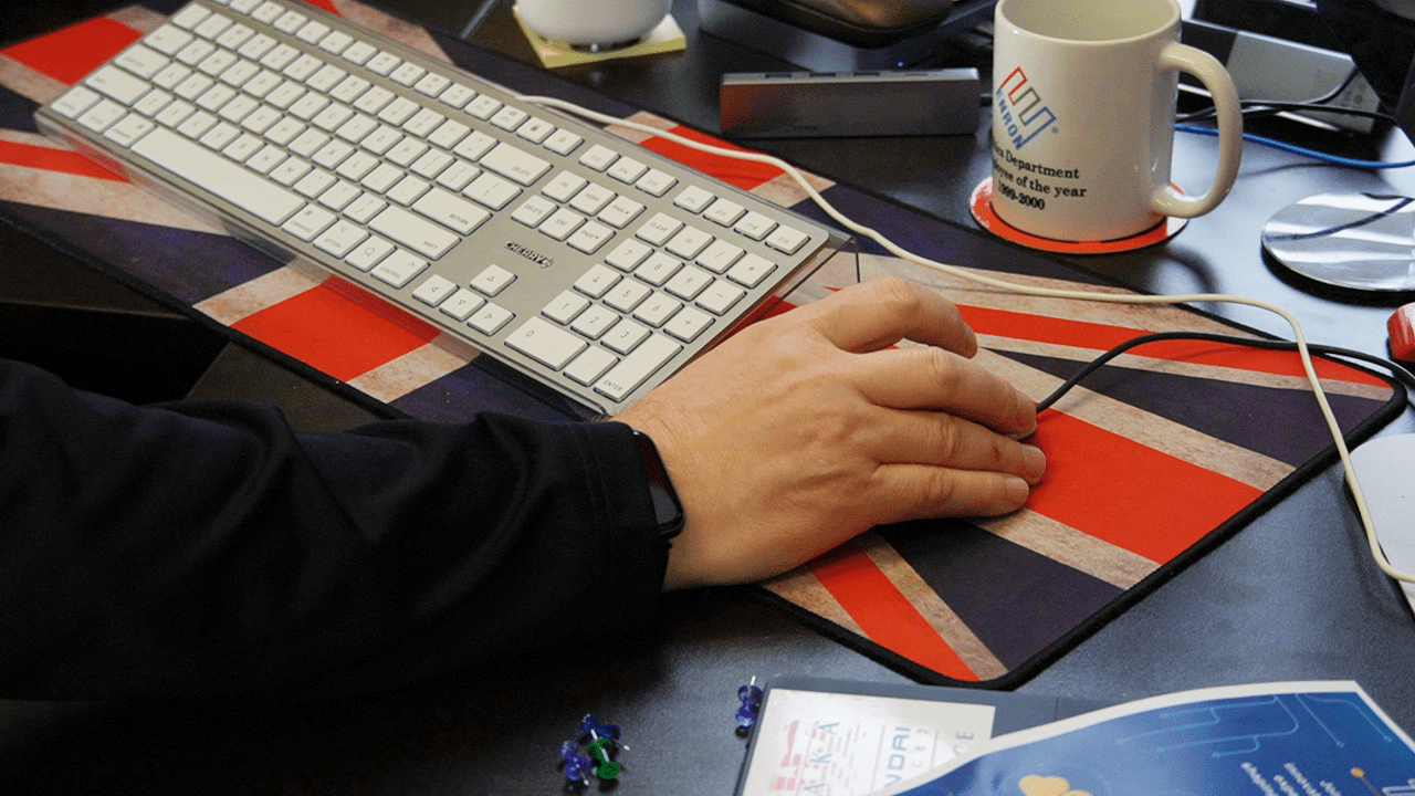 A professor's hand at his keyboard, on top of a Union Jack mousepad.